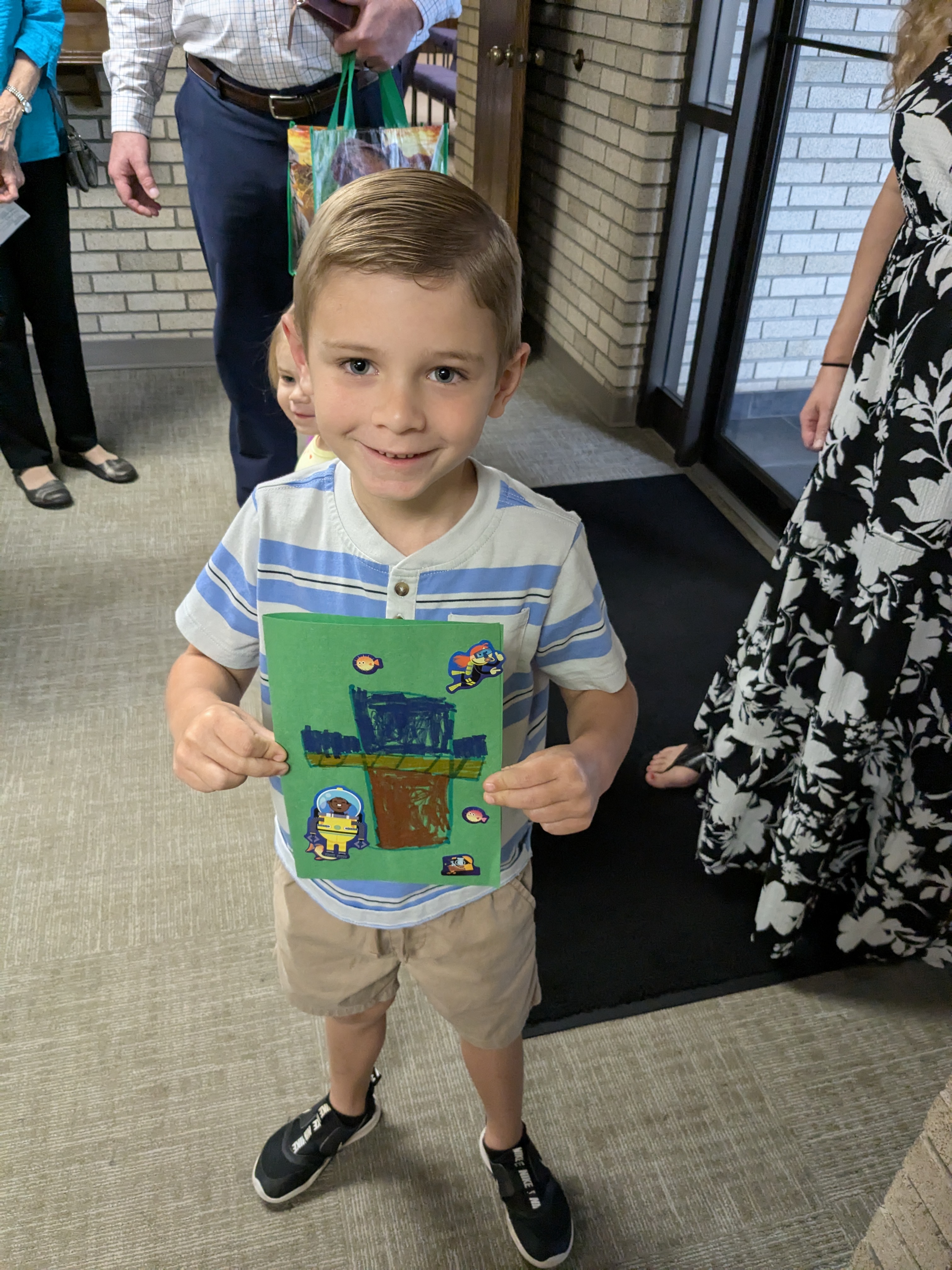 Child proudly showing Sunday School artwork at First Christian Church